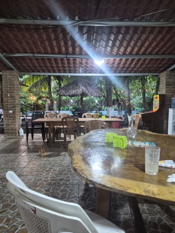 Covered dining terrace with brick columns and wooden tables